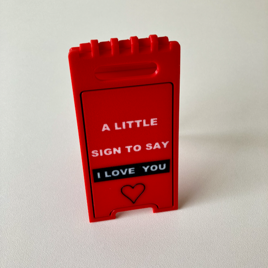 A 3D printed small hinged red Valentine's Day decorative sign with the phrase 'A LITTLE SIGN TO SAY I LOVE YOU'.