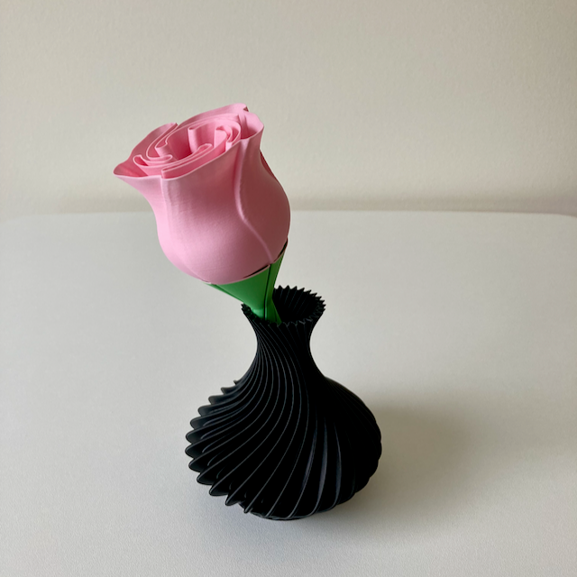 A 3D printed black vase with pink rose Valentine's Day decoration.
