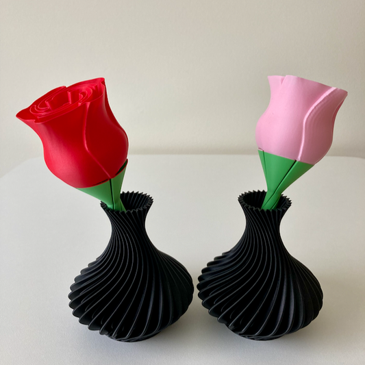 Two 3D printed black vases, a red rose, a pink rose as Valentine's Day decorations.