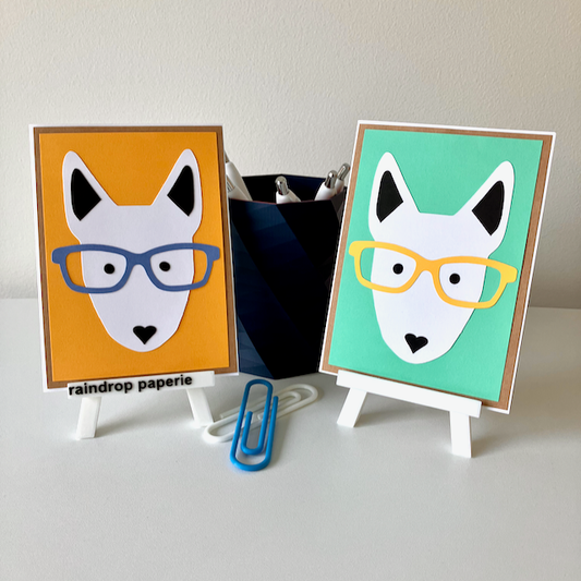 Two handmade greeting cards with English Bull Terrier faces wearing glasses.