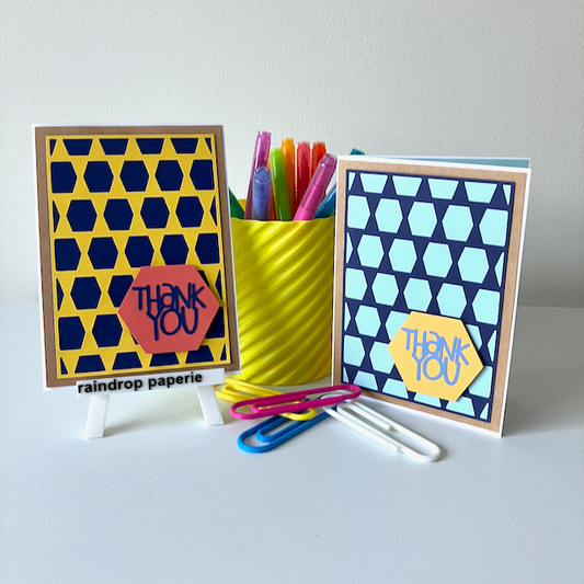 Two handmade greeting cards with geometric patterns and 'Thank You' text displayed with stationery items.
