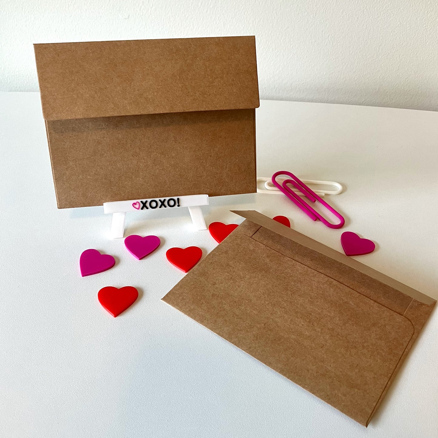 Two kraft envelopes displayed on a table with decorative hearts.