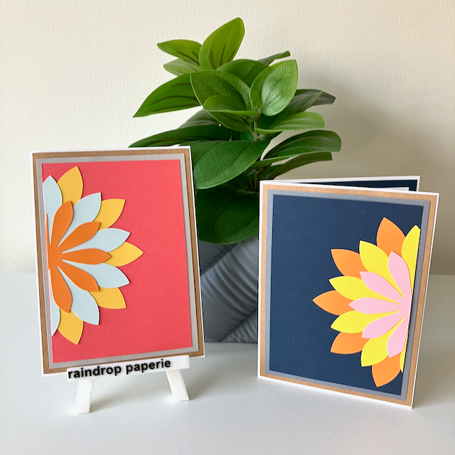 Two handmade greeting cards with a floral design, displayed on a table with a plant in the background.