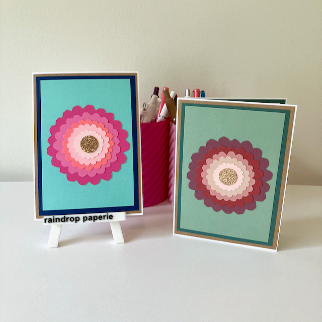 Two handmade greeting cards with large zinnia flowers and glitter centers.