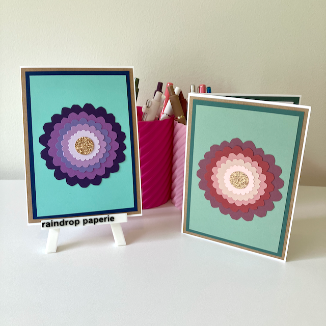 Two handmade greeting cards with large zinnia flowers and glitter centers.