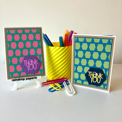 Two handmade greeting cards with geometric patterns and 'Thank You' text  displayed with stationery items.