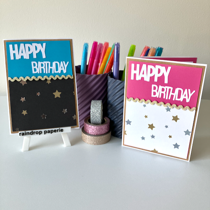 Two 'Happy Birthday' cards with star patterns on a white surface with stationery items.