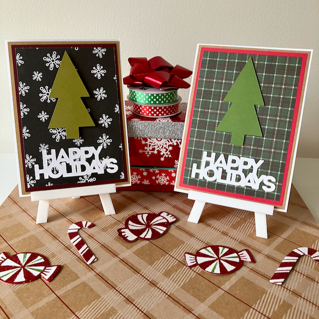 Two 'Happy Holidays' greeting cards with Christmas tree designs on a checkered surface with candy decorations.