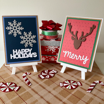 Two Christmas-themed cards on mini easels with decorative ribbons and candy canes on a plaid surface.