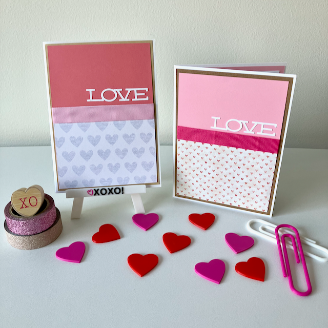 Two handmade greeting cards that say 'Love' displayed on a table with decorative hearts. 