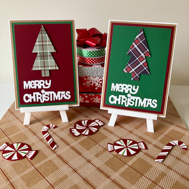 Two Christmas-themed greeting cards on stands with decorative ribbons and candy canes on a plaid surface.