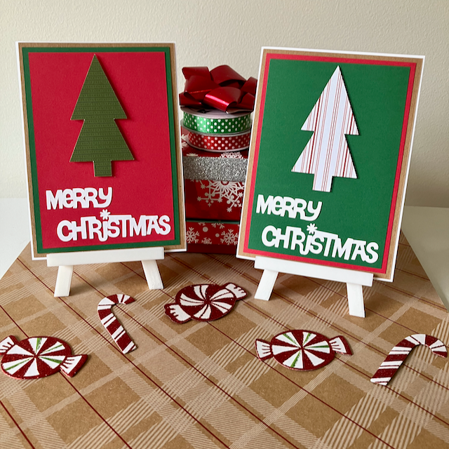 Two Christmas-themed greeting cards on small easels with decorative ribbons and candy canes on a plaid surface.