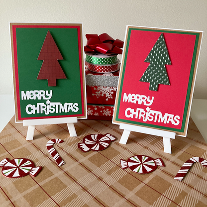 Two Christmas-themed greeting cards on stands with decorative ribbons and candy canes on a checkered surface.