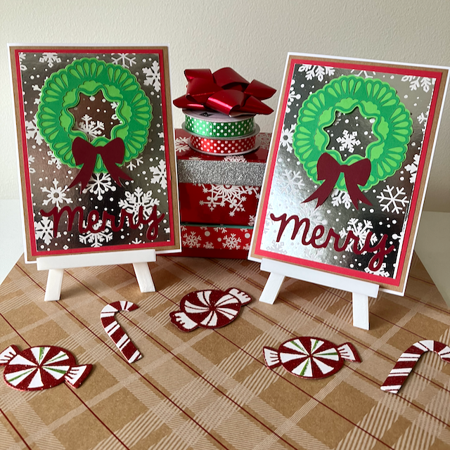 Two Christmas-themed greeting cards with wreaths and 'Merry' text, surrounded by decorative items on a patterned surface.