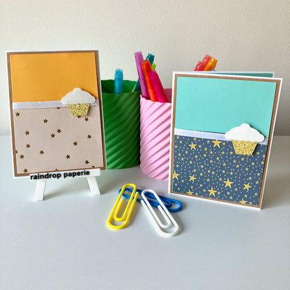Two colorful greeting cards with decorative patterns and a pen holder filled with pens on a white surface.