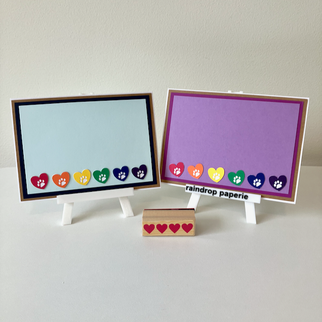 Two handmade greeting cards with hearts and paw prints in rainbow colors. 