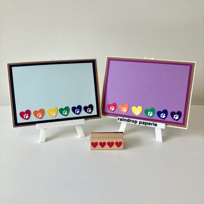 Two handmade greeting cards with hearts and paw prints in rainbow colors. 