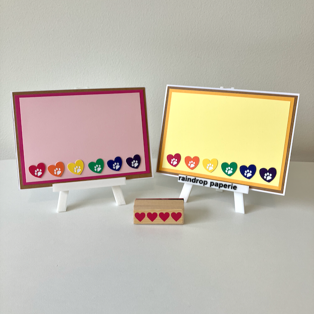 Two handmade greeting cards with hearts and paw prints in rainbow colors. 