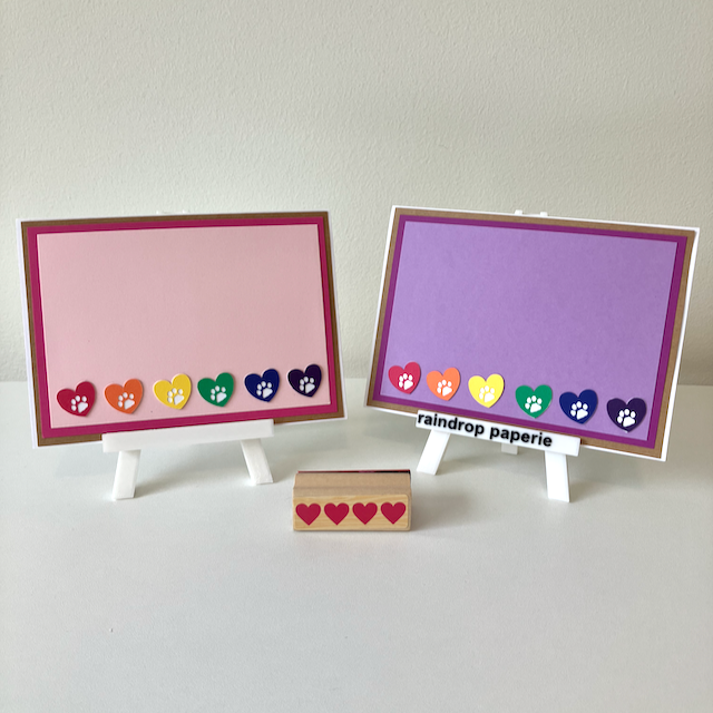 Two handmade greeting cards with hearts and paw prints in rainbow colors. 