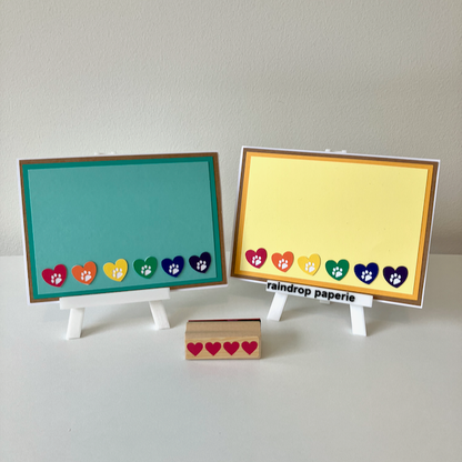 Two handmade greeting cards with hearts and paw prints in rainbow colors. 