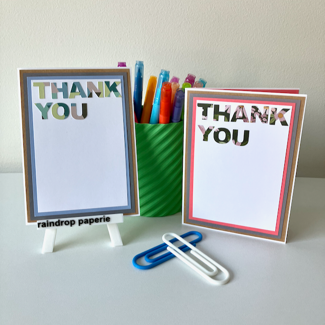 Two 'Thank You' cards with a green cup of colorful markers on a white surface.